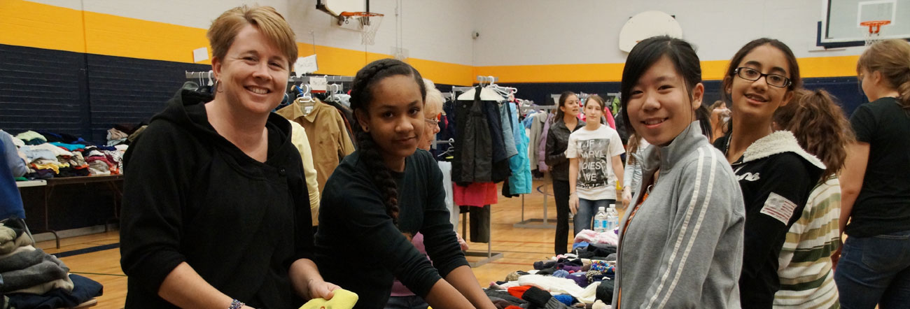 Students and teacher volunteer at a clothing drive